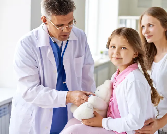 Médico atiende a una niña acompañada de su madre en un examen físico