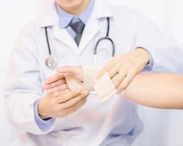 Health professional bandaging a patient's hand and wrist